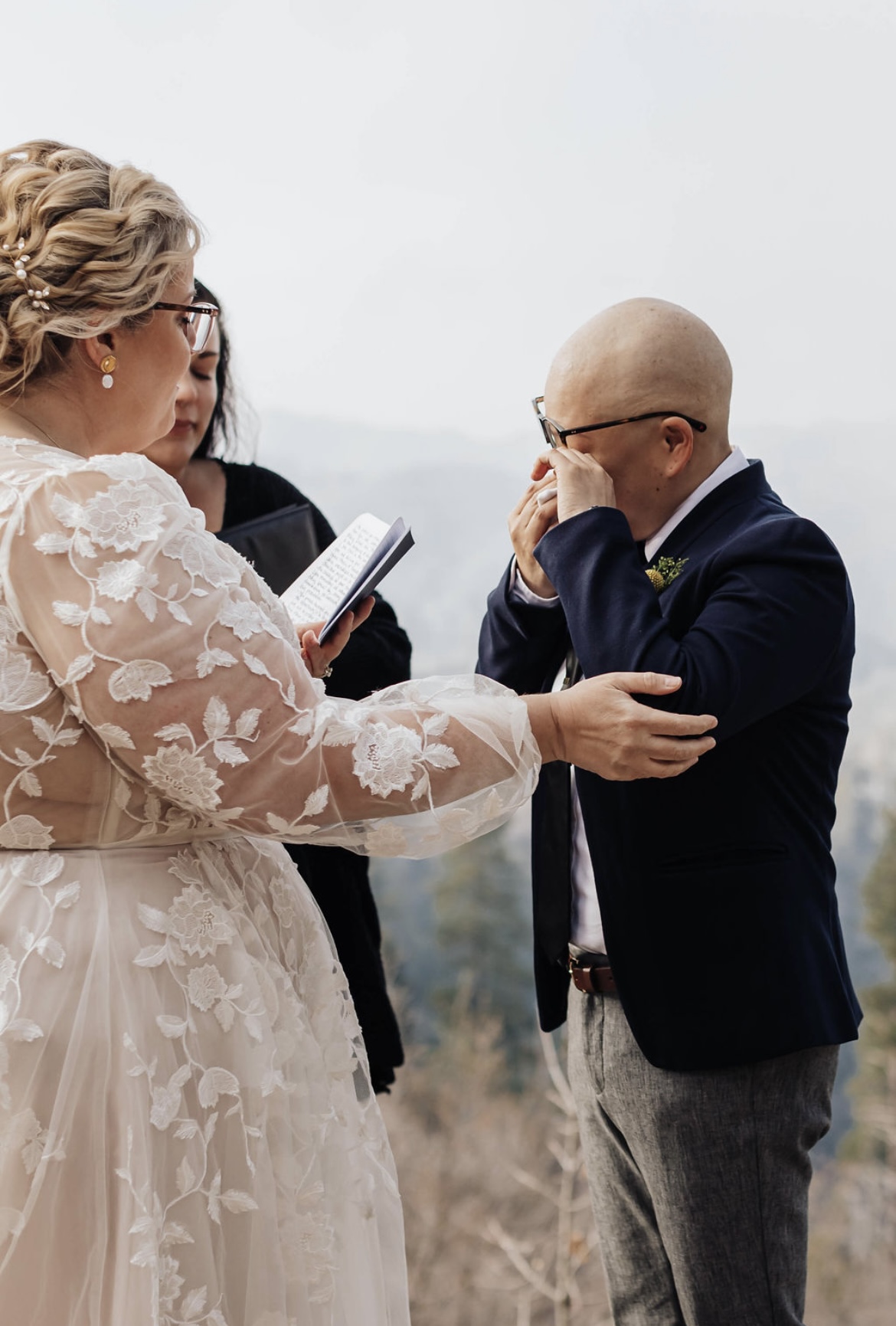 Groom wiping tears while his bride reads her personalized wedding vows
