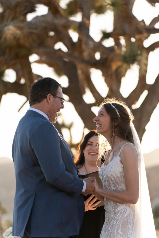 Couple holding hands and exchanging vows with the officiant smiling behind them