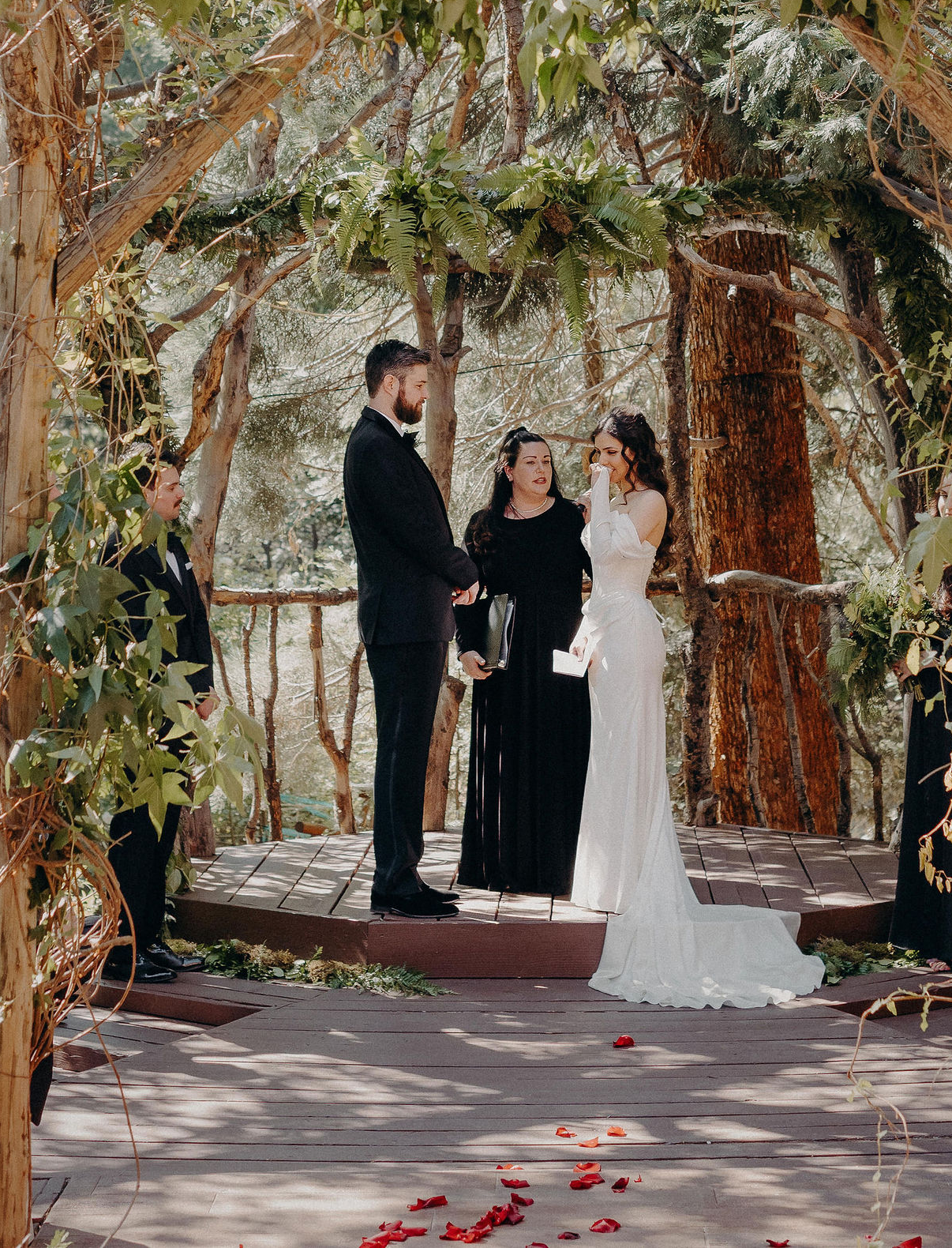 Wedding officiant leading an emotional personalized ceremony for a couple in a wooded setting.